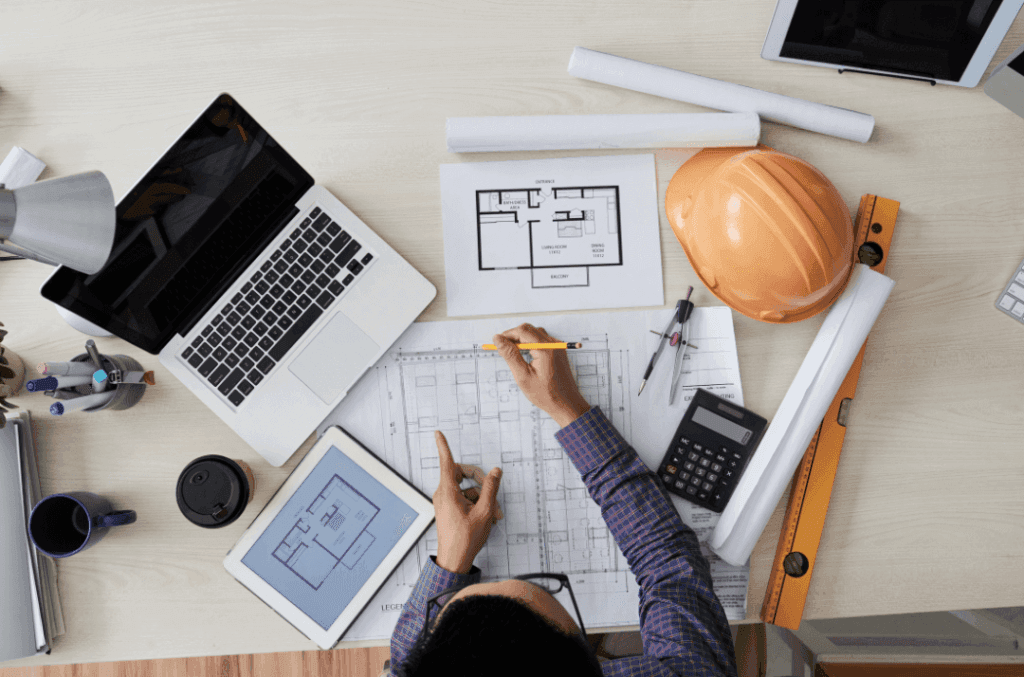 Estimator reviewing construction drawings with a laptop and calculator